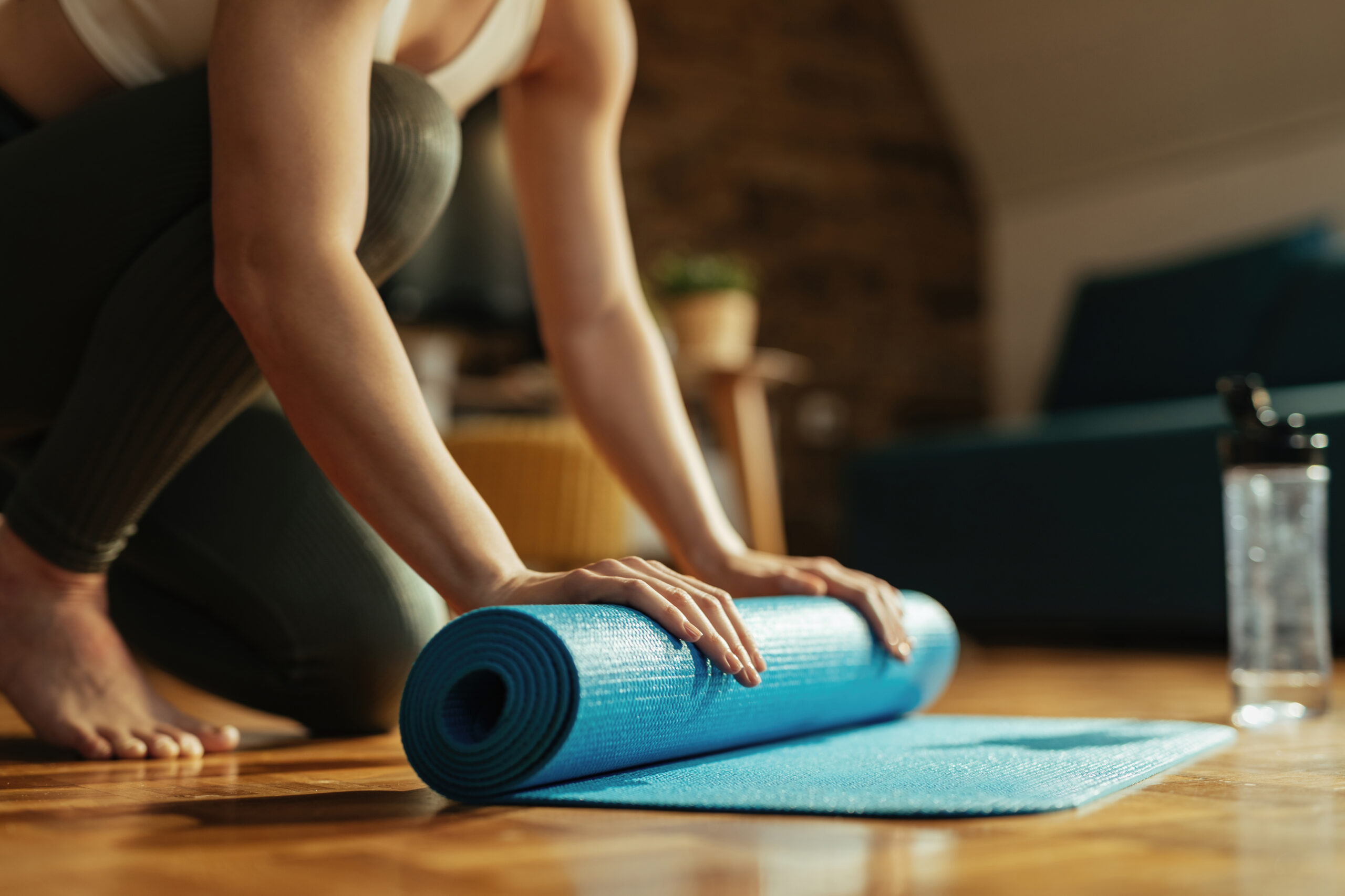 Una dona esportiva irrecognoscible enrotlla l'estora d'exercici després de l'esport deprés de fer pilates MAT